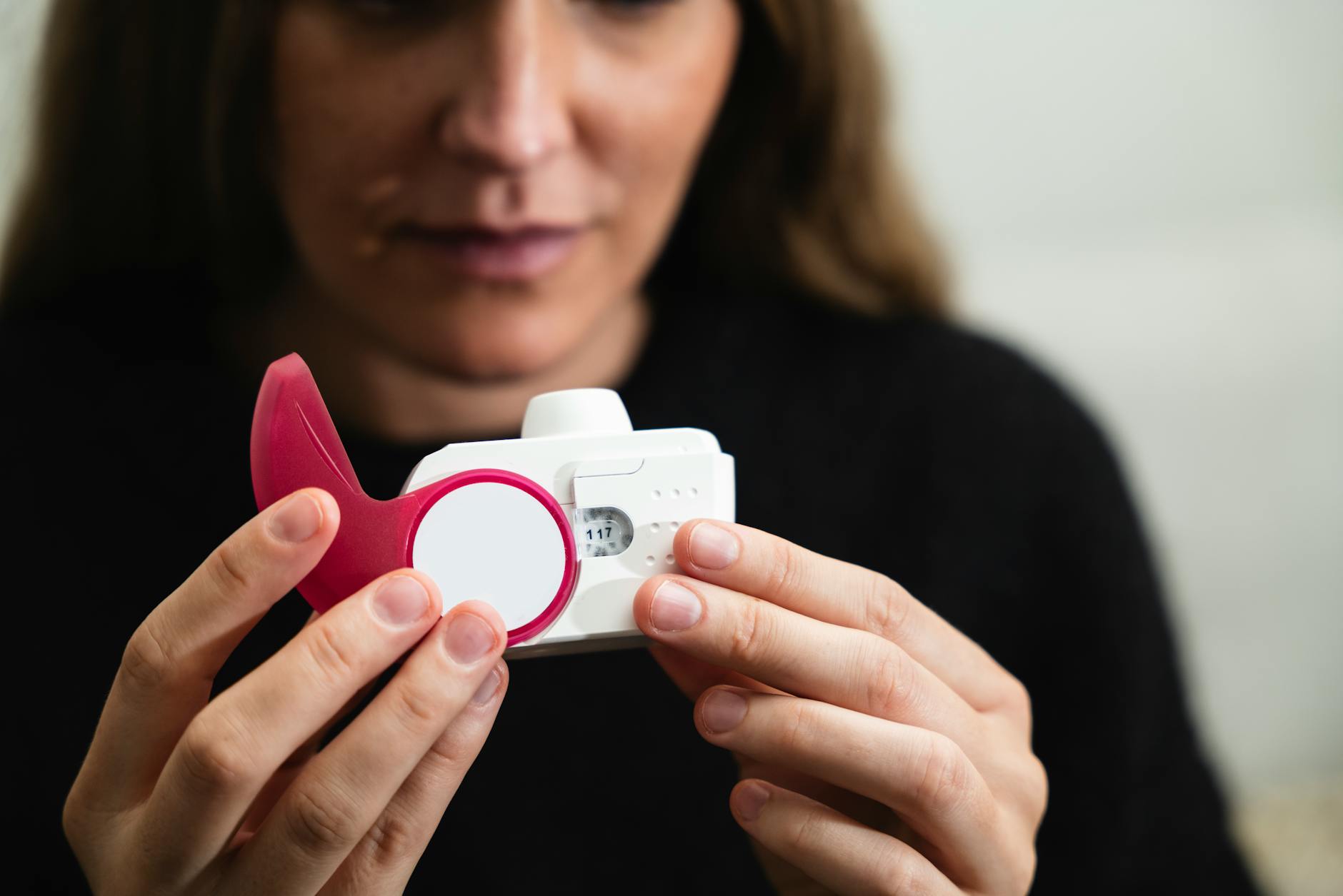 Close-up of a woman holding a medical inhaler device for respiratory conditions.