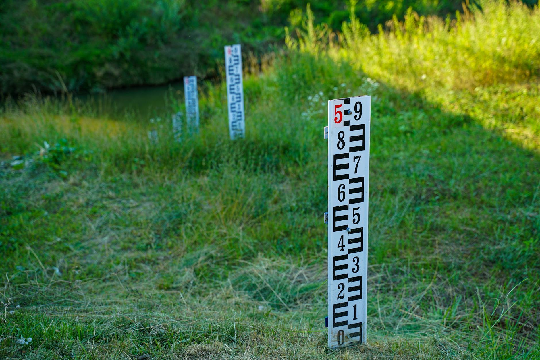 Outdoor water level measurement in a grassy field with clear signage for accurate readings.